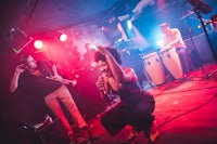 a woman performs on stage in front of a group of musicians